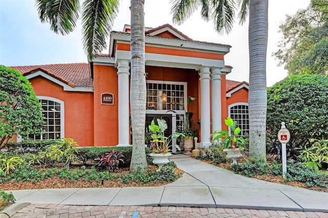 exterior space with stucco siding and a tile roof