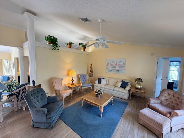 living room featuring visible vents, crown molding, vaulted ceiling, decorative columns, and wood finished floors