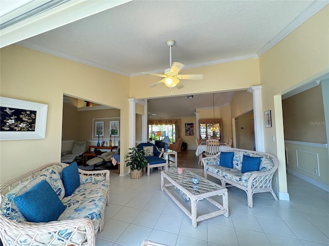 living area with light tile patterned floors, ceiling fan, crown molding, and ornate columns