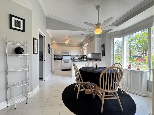 dining room featuring light tile patterned floors, baseboards, crown molding, and vaulted ceiling