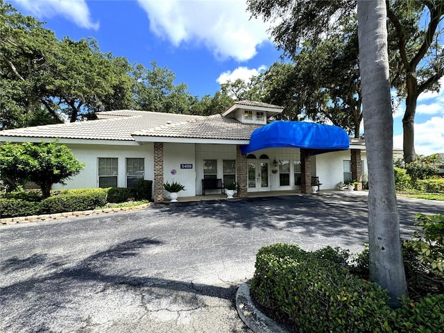 view of front of property with french doors, a tile roof, and stucco siding