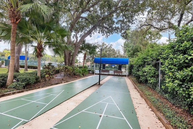 view of community featuring shuffleboard and fence