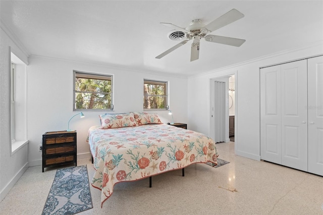 bedroom with a closet, crown molding, speckled floor, and baseboards