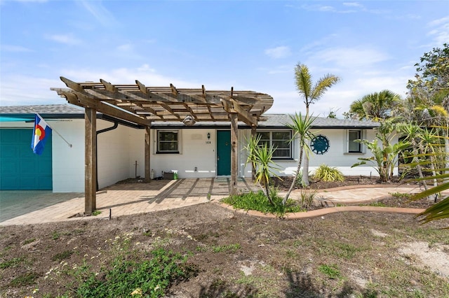 single story home with concrete block siding, an attached garage, and a pergola