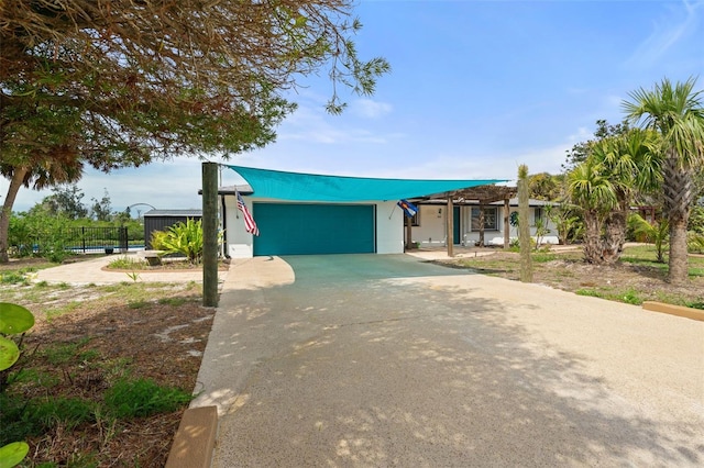 view of front of property featuring concrete driveway, an attached garage, and fence