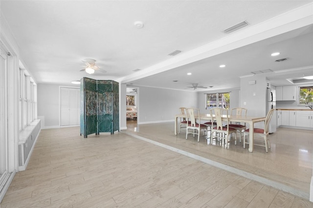 dining area with light wood-type flooring, visible vents, and ceiling fan