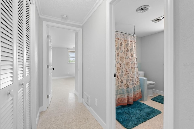 hall with visible vents, baseboards, and a textured ceiling