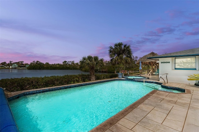 view of swimming pool featuring a water view, a pool with connected hot tub, and a patio area