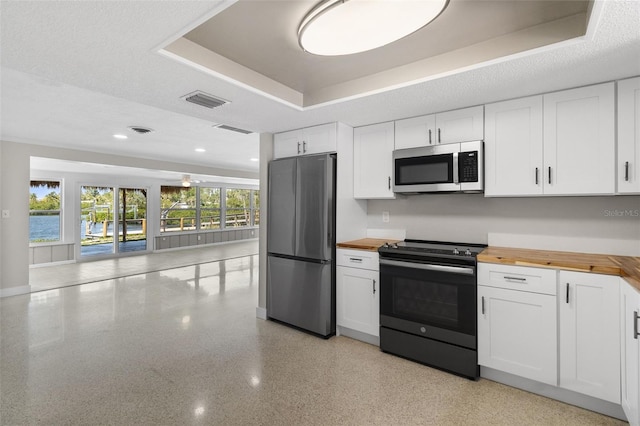 kitchen featuring butcher block counters, visible vents, white cabinetry, and stainless steel appliances