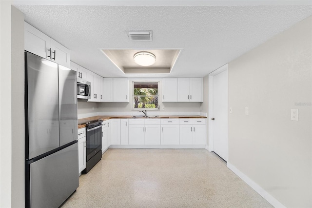 kitchen featuring white cabinets, stainless steel appliances, visible vents, a sink, and baseboards