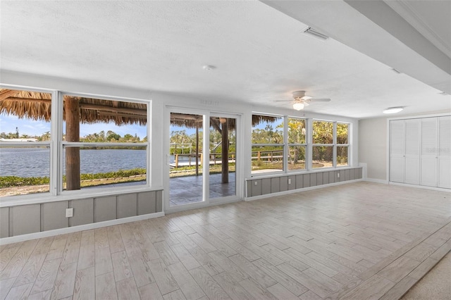 unfurnished sunroom with visible vents, a water view, and a healthy amount of sunlight