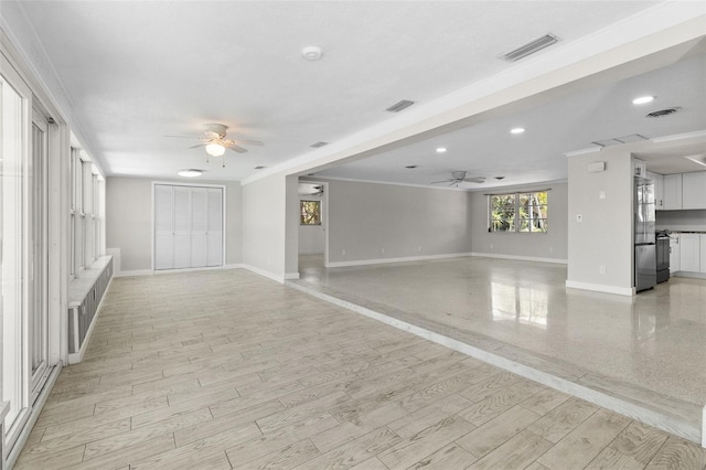 unfurnished living room featuring visible vents, baseboards, and ceiling fan