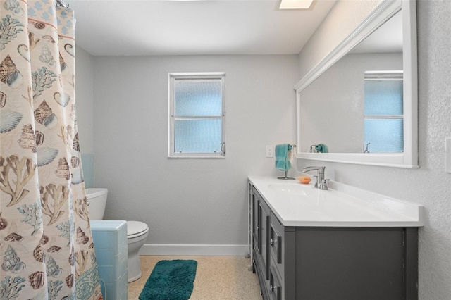 bathroom with baseboards, vanity, speckled floor, and toilet