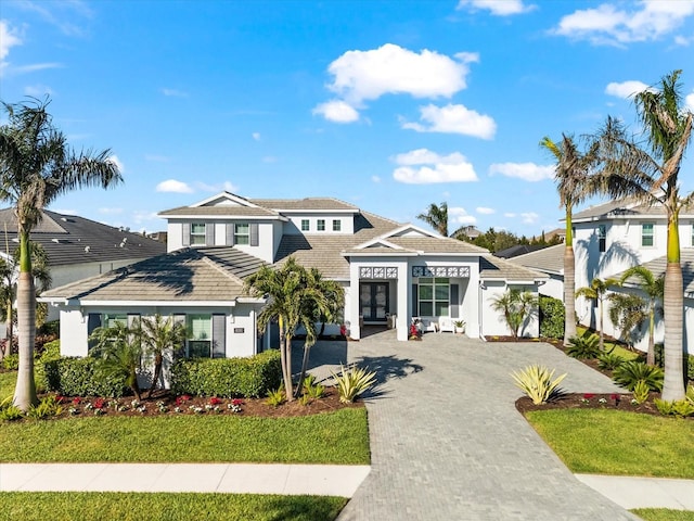 view of front of house with stucco siding, driveway, a tile roof, and french doors