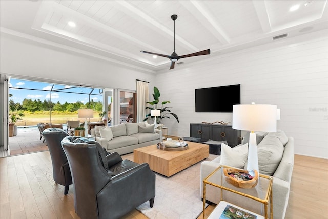 living area with visible vents, beam ceiling, light wood-style flooring, a sunroom, and ceiling fan