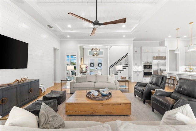 living room featuring light wood finished floors, visible vents, stairs, beam ceiling, and ceiling fan with notable chandelier