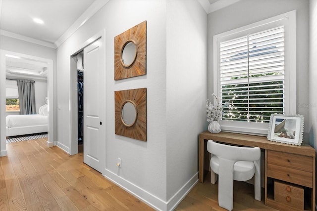 hallway with baseboards, light wood-style floors, and ornamental molding