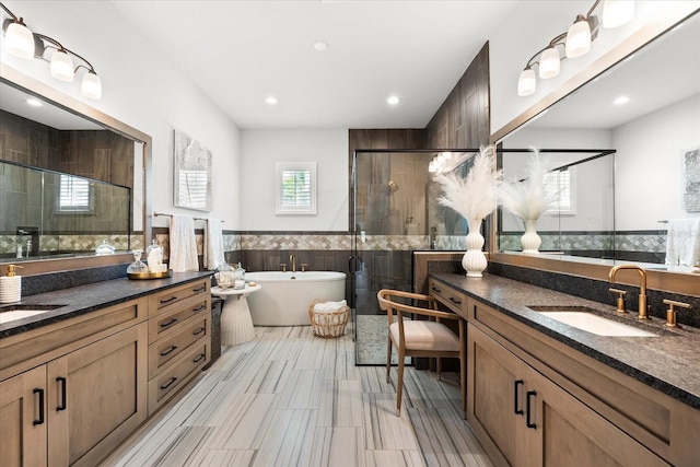 full bath with a sink, a freestanding tub, two vanities, and a stall shower