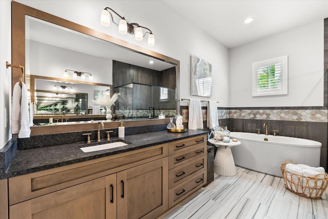 full bathroom featuring a wainscoted wall, tile walls, a shower stall, a soaking tub, and vanity