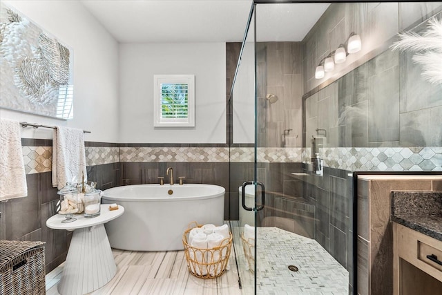 full bathroom featuring a wainscoted wall, a freestanding bath, tile walls, and a stall shower