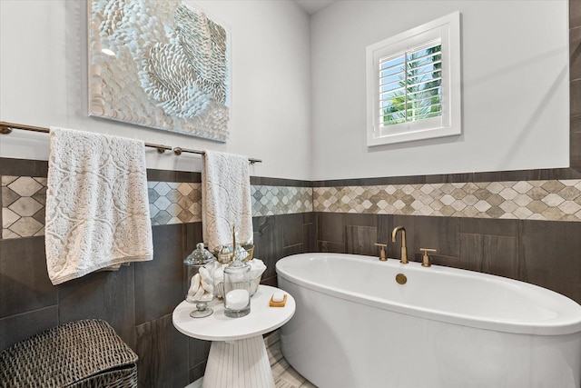 bathroom featuring tile walls, a wainscoted wall, and a freestanding bath