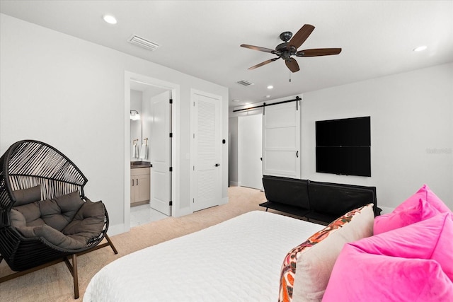 bedroom featuring a barn door, recessed lighting, visible vents, and light carpet