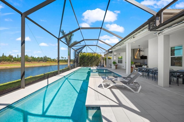 pool featuring glass enclosure, a water view, a ceiling fan, and a patio area