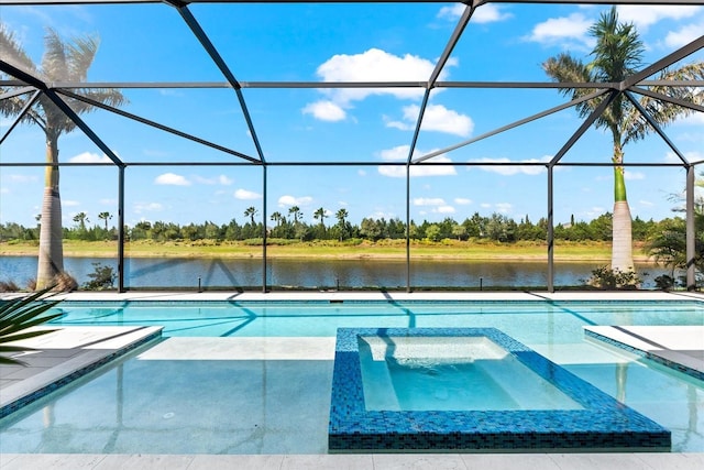 view of pool featuring glass enclosure, a pool with connected hot tub, a patio, and a water view