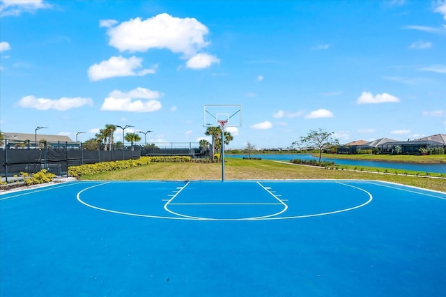 view of basketball court featuring a yard, a water view, community basketball court, and fence