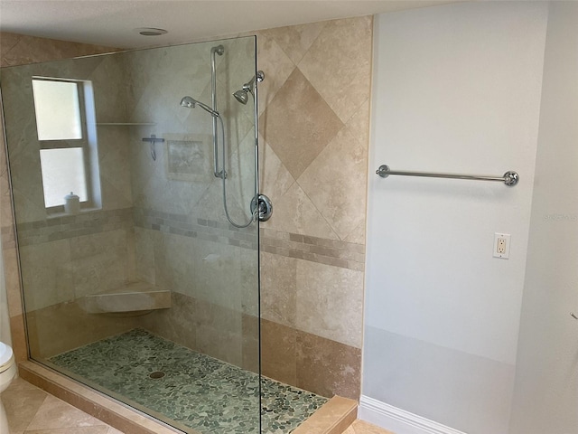 full bathroom featuring tile patterned floors, toilet, and a tile shower