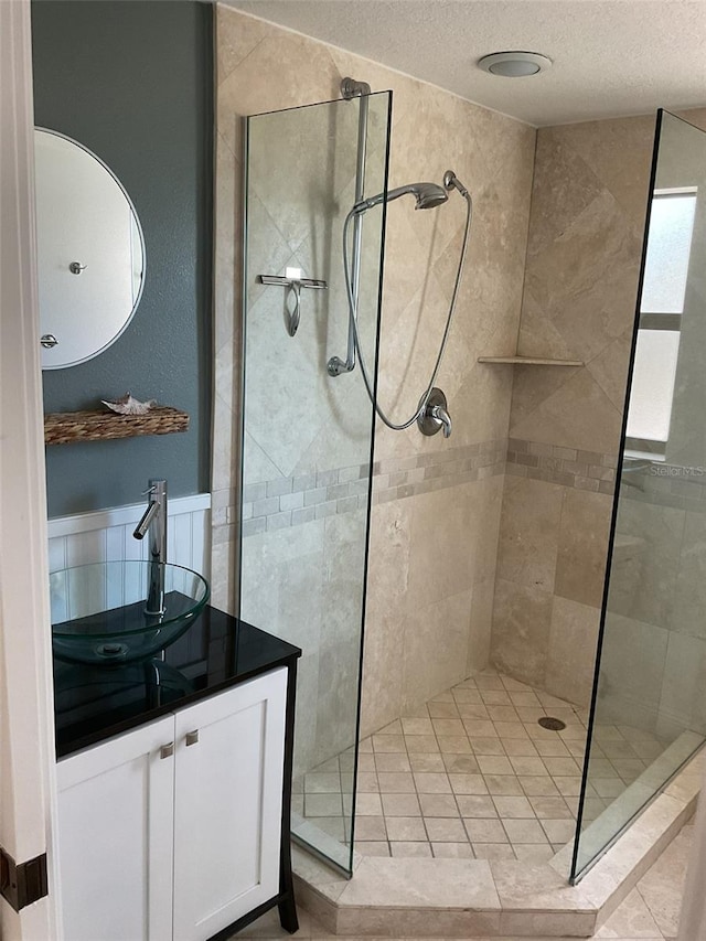 bathroom featuring a textured ceiling, vanity, and walk in shower