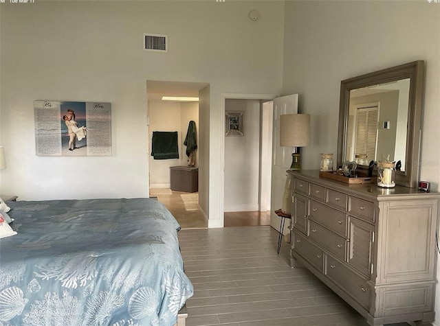 bedroom featuring visible vents, a high ceiling, and wood finished floors