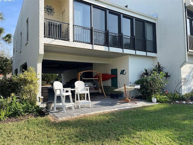 rear view of property with a yard, stucco siding, and a patio