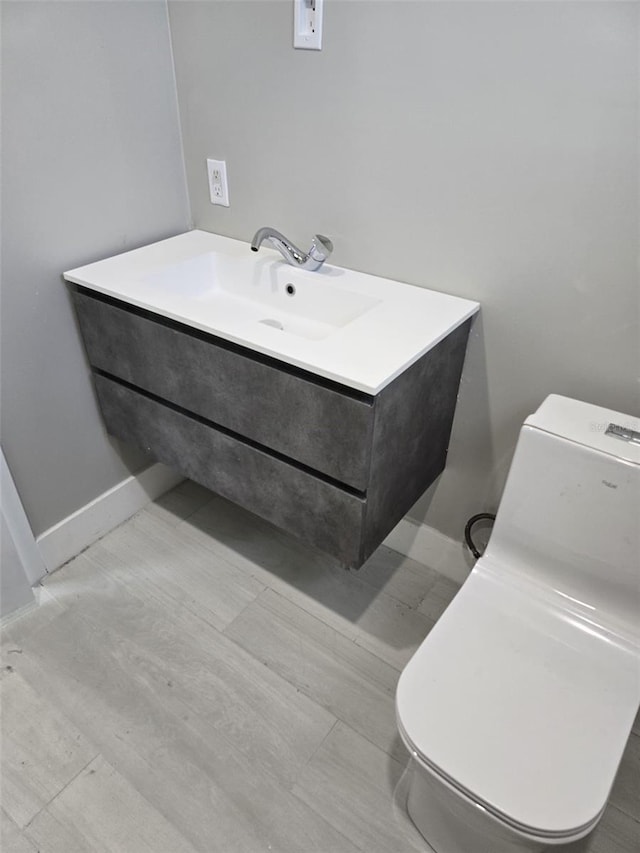 bathroom featuring baseboards, toilet, and vanity