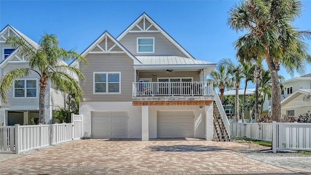 coastal home with stucco siding, a ceiling fan, decorative driveway, fence, and stairs