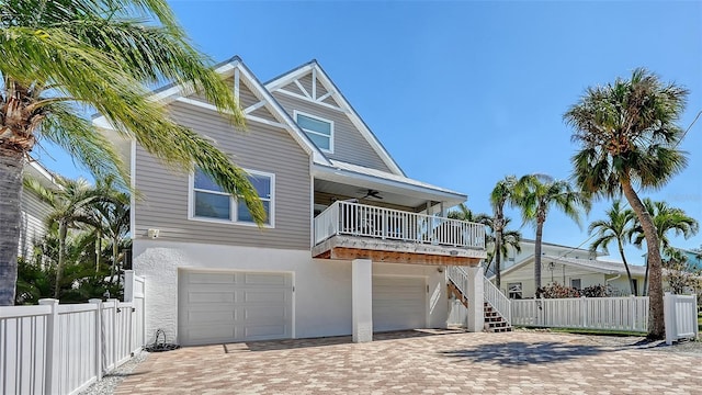 coastal inspired home with stucco siding, an attached garage, ceiling fan, and stairs