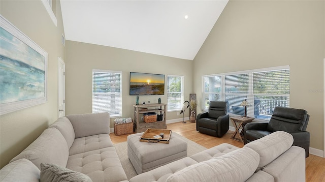 living room featuring baseboards, light wood finished floors, and high vaulted ceiling