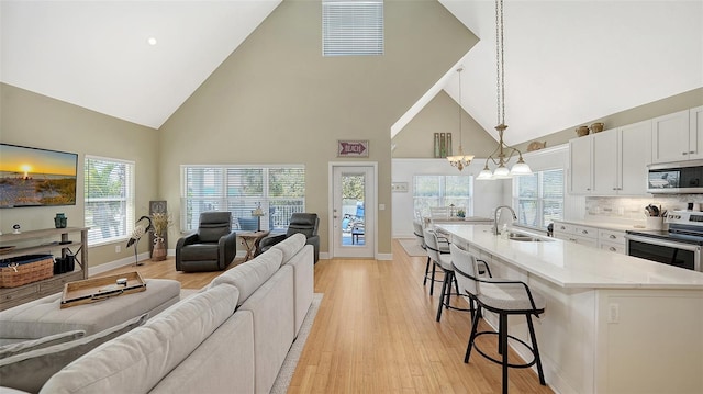 kitchen with light wood-style flooring, a sink, open floor plan, appliances with stainless steel finishes, and a breakfast bar area