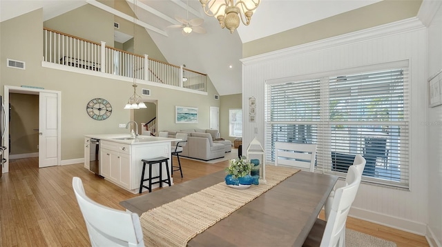 dining area with visible vents, light wood-style flooring, ceiling fan with notable chandelier, and baseboards