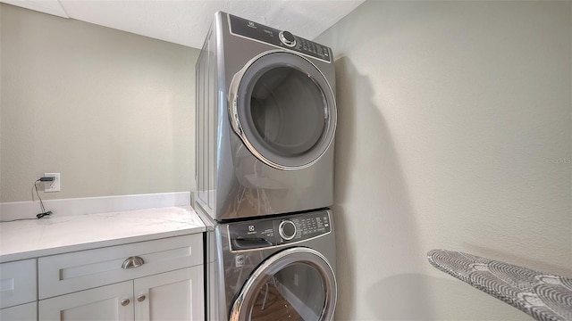 laundry room with stacked washer / dryer and cabinet space