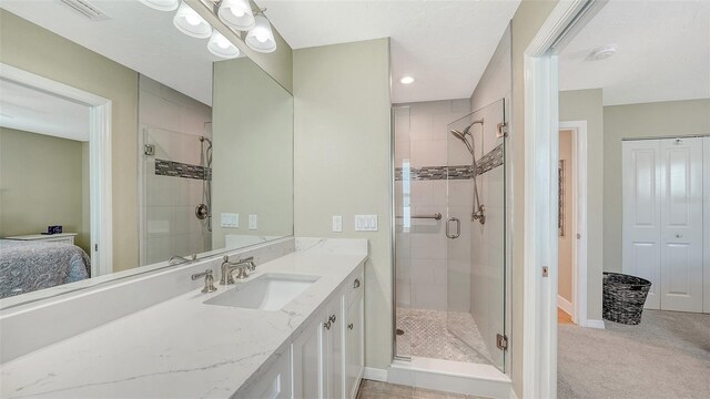 ensuite bathroom with vanity, a shower stall, baseboards, and visible vents