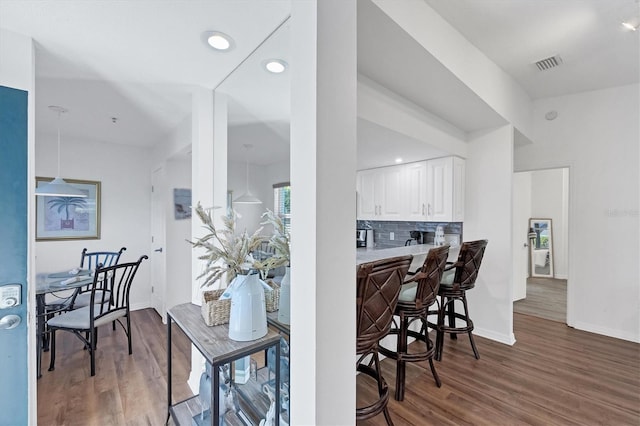 kitchen featuring visible vents, tasteful backsplash, wood finished floors, white cabinets, and baseboards