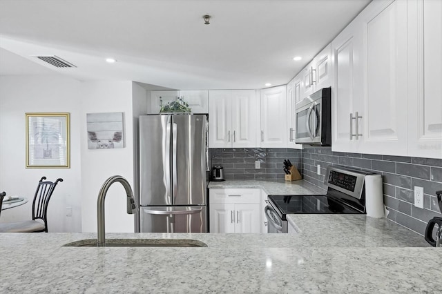 kitchen with backsplash, light stone countertops, stainless steel appliances, and a sink