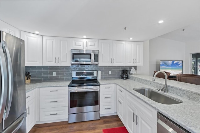 kitchen with a sink, stainless steel appliances, decorative backsplash, light stone countertops, and dark wood-style flooring