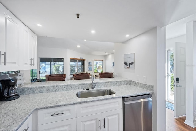 kitchen featuring light wood finished floors, dishwasher, white cabinetry, and a sink