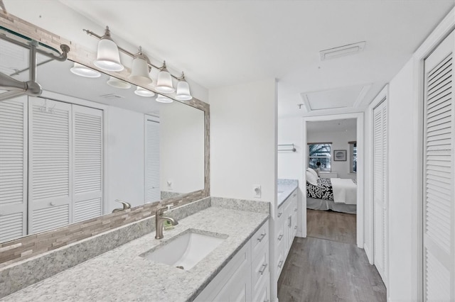 ensuite bathroom with vanity, wood finished floors, visible vents, ensuite bath, and a closet