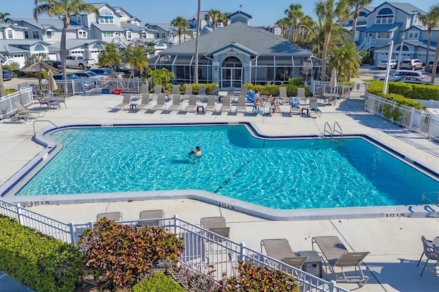 community pool with a residential view, a patio, and fence