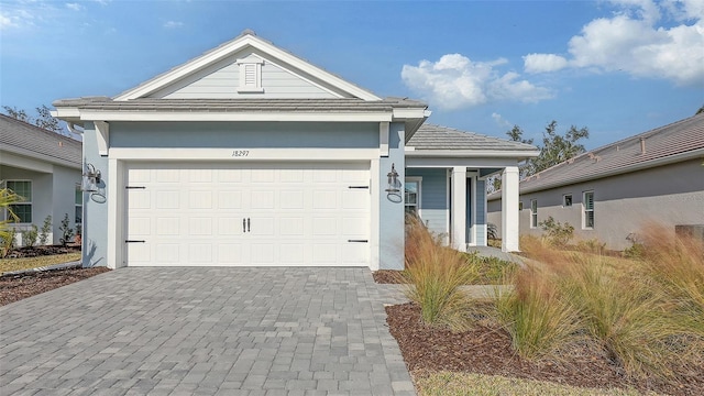 ranch-style house with a tiled roof, decorative driveway, a garage, and stucco siding