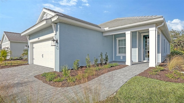 view of home's exterior with stucco siding, an attached garage, and decorative driveway