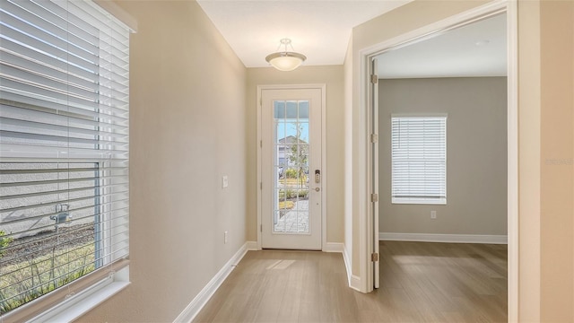 doorway with baseboards and light wood finished floors